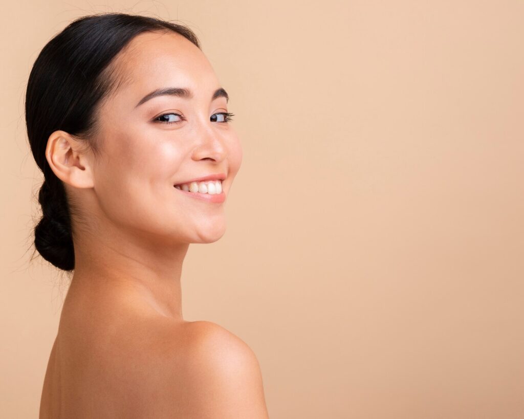Smiling woman with clear skin and a natural glow, showcasing healthy skin care results related to waxing and aesthetic treatments.