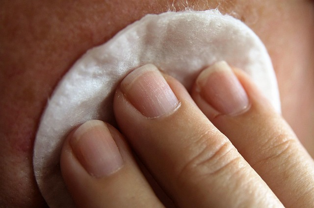 Person using a cotton pad to gently cleanse skin, emphasizing post-waxing care and moisture adjustment.