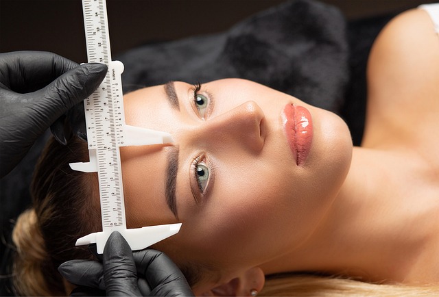 Technician measuring eyebrow shape on a client during eyebrow tinting consultation, showcasing precise mapping for enhanced brow definition and fullness.