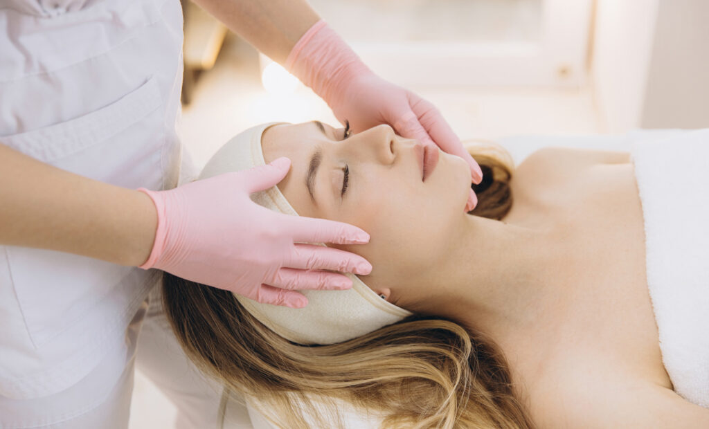 Aesthetician performing a facial treatment on a relaxed client, highlighting professional skincare services for winter waxing care.