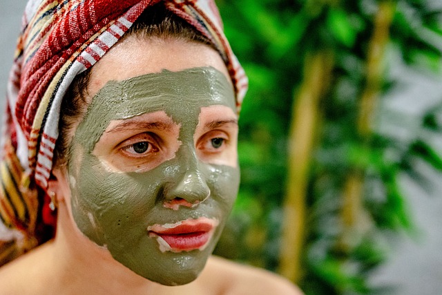 Woman with a green facial mask and a towel on her head, representing skincare treatments related to chemical peels and microneedling for rejuvenation.